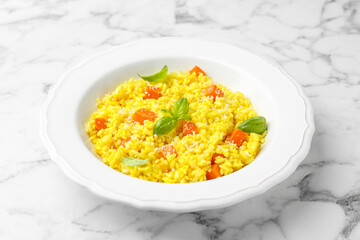Delicious pumpkin risotto on white marble table, closeup