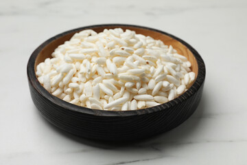 Puffed rice in bowl on white marble table, closeup