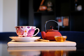 Floral teacup and red teapot on a wooden board a moment of tranquility