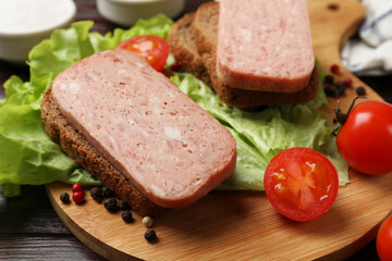 Tasty canned meat, bread, tomatoes, spices and lettuce on wooden table, closeup