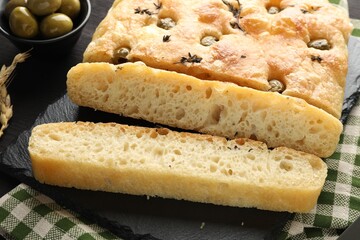 Pieces of delicious focaccia bread with olives and thyme on table, closeup