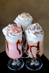 Three creamy iced drinks with whipped cream and chocolate drizzle