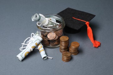 Dollar banknotes, coins and graduate hat on grey table. Tuition payment