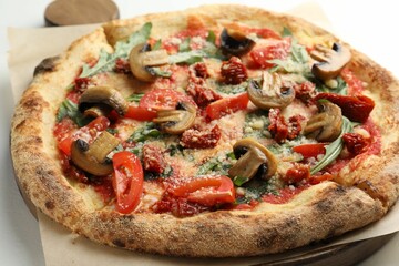 Tasty pizza with mushrooms, tomatoes and arugula on white table, closeup