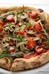 Tasty pizza with mushrooms, tomatoes and arugula on white table, closeup
