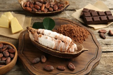 Cocoa pod with beans, powder, chocolate and butter on wooden table, closeup