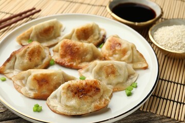 Delicious fried gyoza dumplings with green onions served on table, closeup