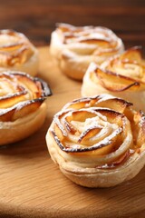 Freshly baked apple roses on wooden board, closeup