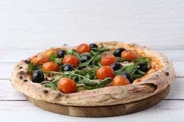 Tasty pizza with cherry tomatoes, black olives, mushrooms and arugula on white wooden table, closeup