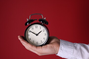 Man with alarm clock on red background, closeup