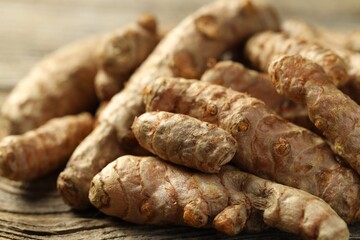 Pile of tumeric rhizomes on wooden table, closeup