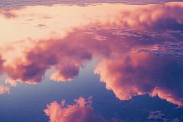 Pink and purple sunset clouds reflected on calm water, creating a serene and beautiful scene.