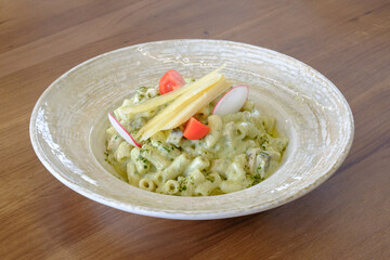 Creamy pasta dish with vegetables and cheese garnished with radish and tomato slices