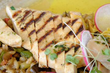 Grilled chicken breast sliced and served atop a bed of sauteed vegetables
