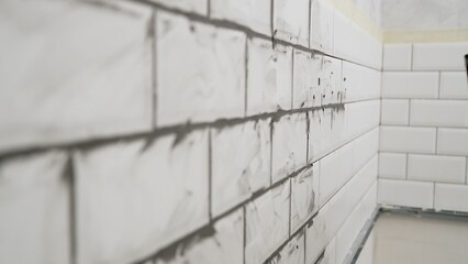 Laying white ceramic tiles on the wall with grout