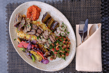 Grilled meat and vegetable platter with various dips and salads