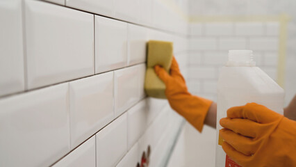 Cleaning person washing white ceramic tiles with detergent and sponge