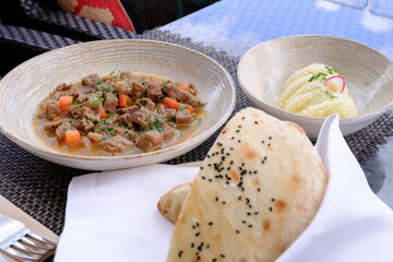 Hearty stew with tender meat carrots and fresh herbs served with fluffy mashed potatoes and a warm flatbread