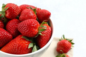 Delicious fresh red strawberries in a bowl on a wooden background