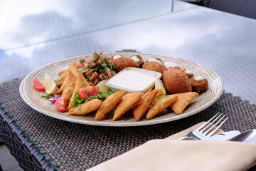 A delicious platter of savory pastries falafel and a creamy dip garnished with fresh herbs and vegetables