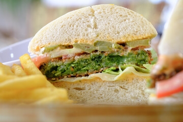A delicious veggie burger on a bun with lettuce tomato and pickles served with a side of french fries