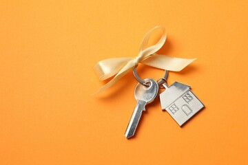 Metallic key with keychain in shape of house on color background