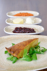 A slice of cornbread served with fresh greens and various accompaniments