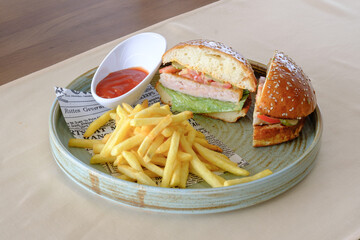A delicious looking burger and fries served with ketchup on a rustic plate