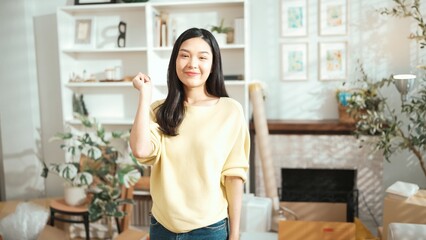Young entrepreneur holding the key as ownership while standing at home office. Happy female seller looking at camera with confidence while moving key for managing small business or start up. Myrmidon.