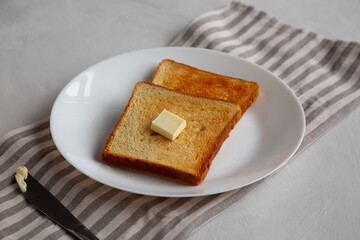 Homemade Toasted Bread Slice with Butter on a Plate, side view.
