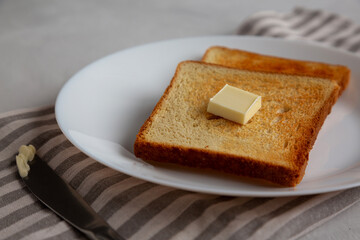 Homemade Toasted Bread Slice with Butter on a Plate, low angle view.