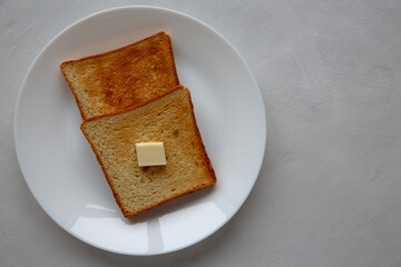 Homemade Toasted Bread Slice with Butter on a Plate, top view.