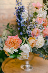 Beautiful floral arrangement featuring pastel roses and wildflowers in a clear vase on a wooden table