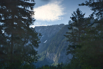 Reflection of mountain framed by trees in a lake in Bluntautal Valley on a spring evening in Austria.