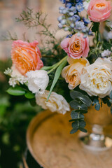 Bright floral arrangement featuring roses and seasonal blooms in a rustic setting surrounded by greenery