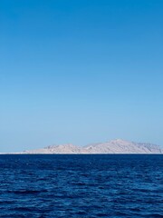 The vibrant Red Sea in Egypt, featuring crystal-clear blue waters teeming with corals, framed by the stark desert and majestic mountains in the background.