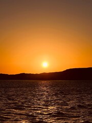 A breathtaking sunset over the Red Sea in Egypt, with vibrant colors reflecting on the water, framed by the desert and majestic mountains in the background.