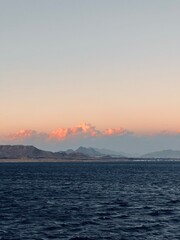 A breathtaking sunset over the Red Sea in Egypt, with vibrant colors reflecting on the water, framed by the desert and majestic mountains in the background.