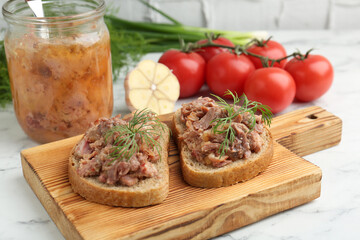Sandwiches with canned meat, dill, garlic and tomatoes on white marble table, closeup