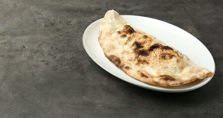 One delicious calzone on grey textured table, space for text