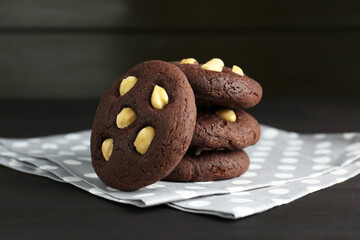Delicious chocolate cookies with hazelnuts on black wooden table, closeup