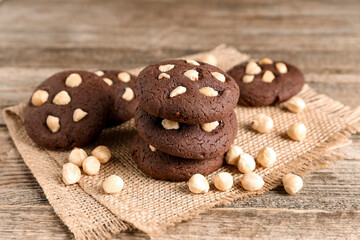 Tasty chocolate cookies with hazelnuts on wooden table, closeup