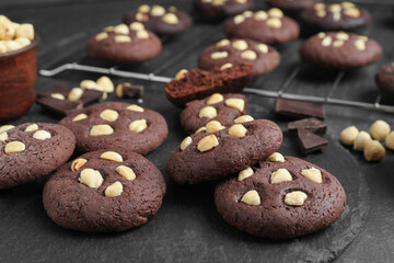 Tasty chocolate cookies with hazelnuts on black table, closeup