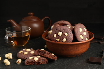 Tasty chocolate cookies with hazelnuts and tea on black table
