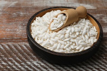 Puffed rice in bowl and scoop on wooden table, closeup