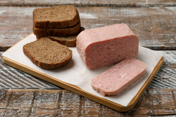 Canned meat and bread on wooden table, closeup