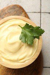 Delicious mayonnaise sauce with parsley in bowl on tiled table, top view