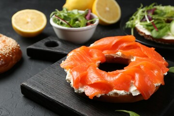 Delicious bagel with salmon and cream cheese n black table, closeup