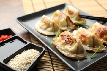 Delicious fried gyoza dumplings with sesame seeds served on table, closeup