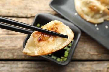 Eating fried gyoza dumplings at wooden table, closeup